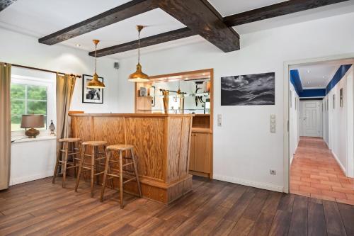 a kitchen with a wooden counter and stools at GUT KLETKAMP "Altes Backhaus" - Freistehendes Landhaus mit 7 Schlafzimmern I Kamin I Garten & Terrasse I 15 Min zur Ostsee I Parkplätze I Hundefreundlich I Bar I WLAN in Kletkamp