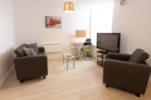 a living room with two chairs and a flat screen tv at Cosy Studio Apt in Preston near City Centre in Preston