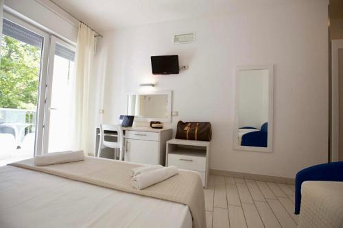 a bedroom with a bed and a desk with a mirror at Hotel Elite in Cervia