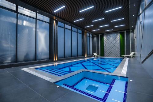 a swimming pool with blue tiles in a room with windows at PREMIER HOTEL in Andijan
