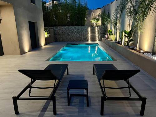 une piscine avec deux chaises et une table dans l'établissement Magnifique villa contemporaine, à Fréjus