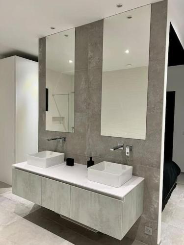 une salle de bain avec deux lavabos et un miroir dans l'établissement Magnifique villa contemporaine, à Fréjus