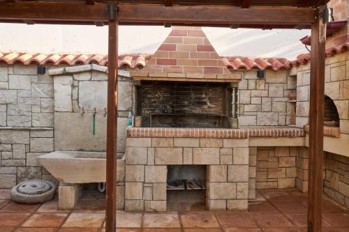 an outdoor kitchen with a stone fireplace and a sink at Villa Irini in Patsídhes