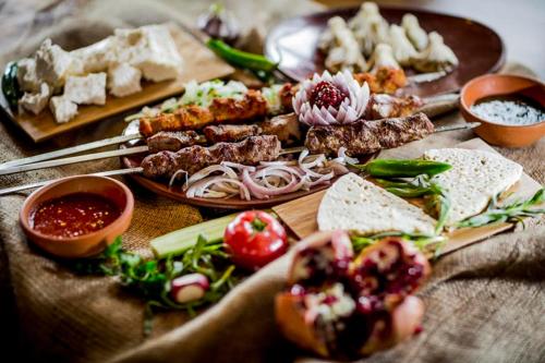 a table topped with different types of food on plates at Super Lux Apartment Mgzavrebi in Gonio