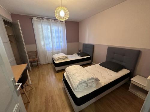 - une chambre avec 2 lits, une table et un lustre dans l'établissement Joli T4 Saint Martin D'Hères, à La Tronche