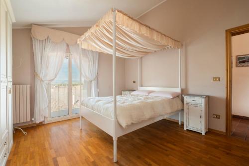 um quarto com uma cama de dossel e uma janela em La Gipsofila Attic em Osimo