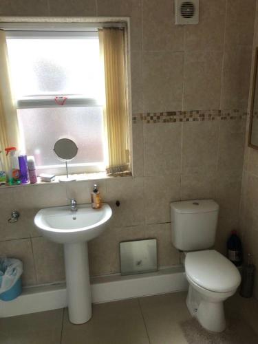 a bathroom with a toilet and a sink and a window at Room in town centre in Saint Helens