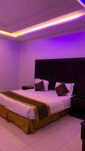 a bedroom with a large bed with purple lighting at رتان للشقق المخدومة in Khamis Mushayt