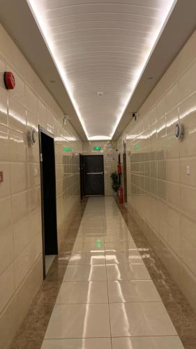 a long hallway with a door in a building with tiles at رتان للشقق المخدومة in Khamis Mushayt