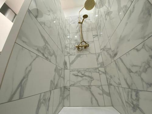 La salle de bains est pourvue de murs en marbre blanc et d'une douche. dans l'établissement Le Royaume des anges - Logement enchanteur centre - 265, à Rouen