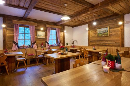 een restaurant met houten tafels, stoelen en ramen bij Eko hiša-Eco House Na razpotju in Solčava