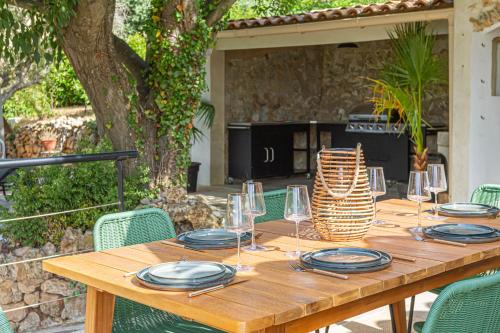 einen Holztisch mit Tellern und Weingläsern darauf in der Unterkunft La Villa Jausserane in Toulon