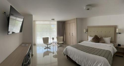 a bedroom with a bed and a table and chairs at Hotel Juan Maria in Tuluá