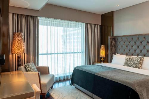 a hotel room with a bed and a chair and a window at Le Meridien City Centre Bahrain in Manama