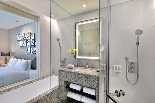 uma casa de banho com uma cama, um lavatório e um chuveiro em Le Méridien City Centre Bahrain em Manama