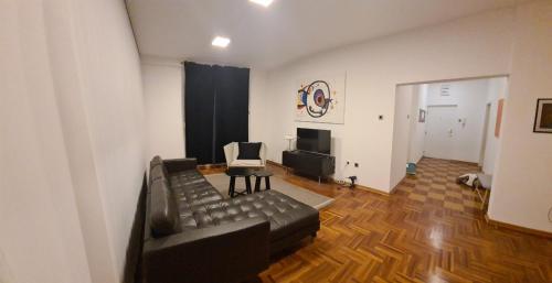 een woonkamer met een zwarte leren bank en een stoel bij Tesa in Novi Beograd