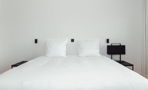 a white bed with white sheets and pillows at CH Longstay 33 in Kortrijk