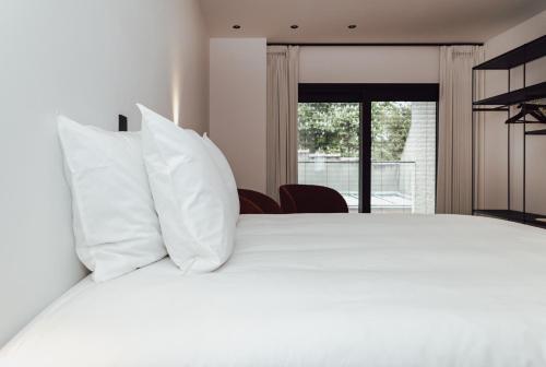 una camera da letto con un letto bianco con cuscini bianchi di CH Longstay 33 a Courtrai