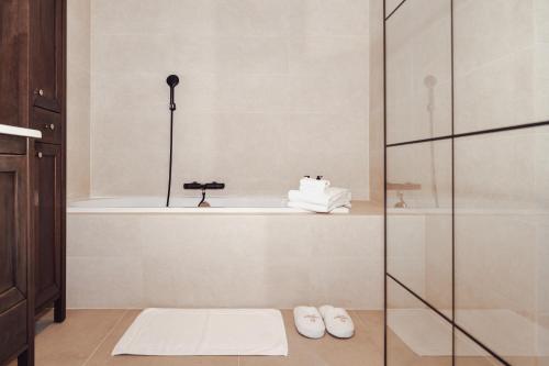 uma casa de banho com uma banheira e um chuveiro com chinelos em CH Longstay 33 em Kortrijk