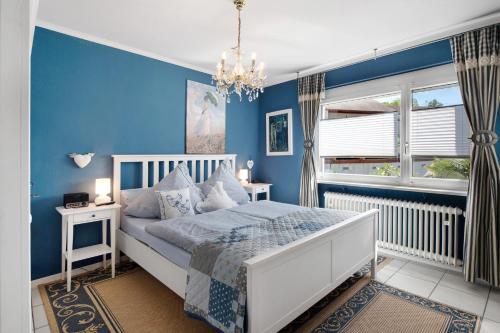 Dormitorio azul con cama y lámpara de araña en Bluehome Ferienwohnung, en Bad Bellingen