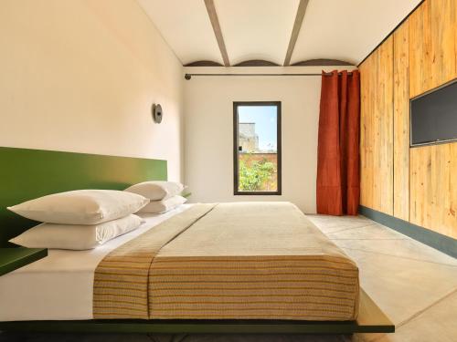 a bedroom with a large bed with pillows and a television at Otro Oaxaca, a Member of Design Hotels in Oaxaca City