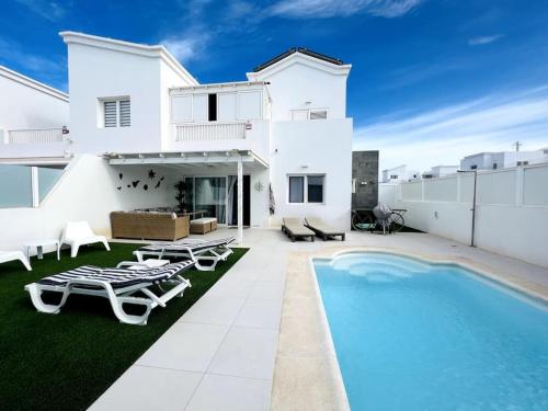 a white house with a swimming pool in front of it at Lovely Villa Sanmar, heated pool in Playa Blanca