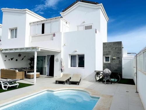 uma casa branca com uma piscina em frente em Lovely Villa Sanmar, heated pool em Playa Blanca