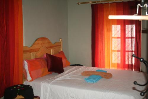 a bedroom with a bed with white sheets and orange curtains at Maggaman Guest House in Tafraoute Sidi Ali