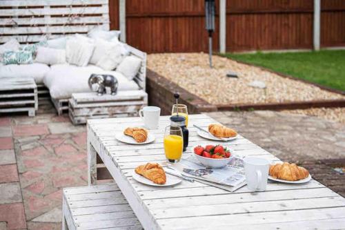 a picnic table with plates of food and orange juice at Beach Retreat Cottage- huge Garden Child & Dog friendly in Broadstairs