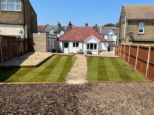 a yard with a fence and a house at Kingsgate Bay Bungalow - 950meter to Beach Dog friendly in Kent
