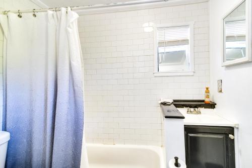 uma casa de banho branca com uma cortina de chuveiro azul em Remodeled Seminole Apt and Yard 3 Mi to Beach! em Redington Shores