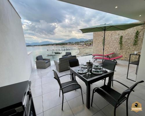 eine Terrasse mit einem Tisch mit Stühlen und einem Sonnenschirm in der Unterkunft Le Galatée Porticcio in Porticcio