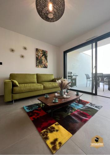 un salon avec un canapé vert et une table dans l'établissement Le Galatée Porticcio, à Porticcio