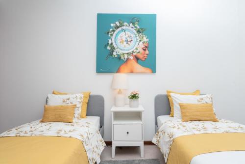 a bedroom with two beds and a painting on the wall at Sunny Cozy Flat w/ Terrace - São João in Porto