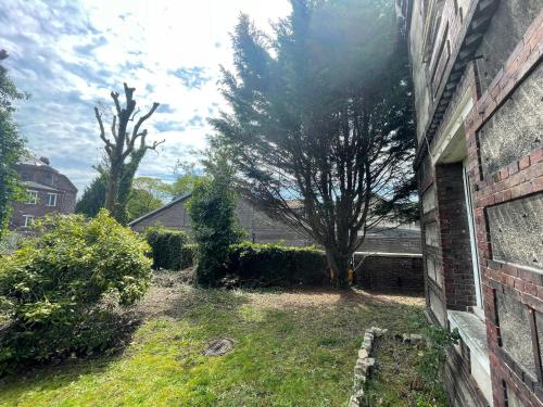 a yard next to a brick building with a tree at La Maison du Directeur - 224 in Déville-lès-Rouen