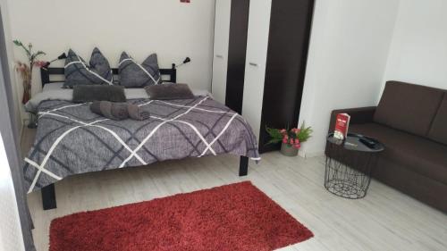 a bedroom with a bed with a red rug and a couch at Vila ANA in Cluj-Napoca