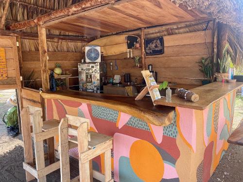 a bar in a wooden house with a counter and chairs at Calypso cabanas in El Paredón Buena Vista