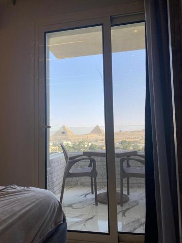 a bedroom with a sliding glass door with a table and chairs at pyramids grand museum inn in Cairo