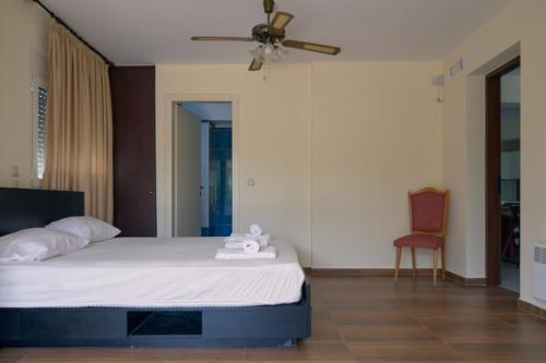 a bedroom with a bed with a ceiling fan and a chair at Green House Marathon - Greece in Nea Makri