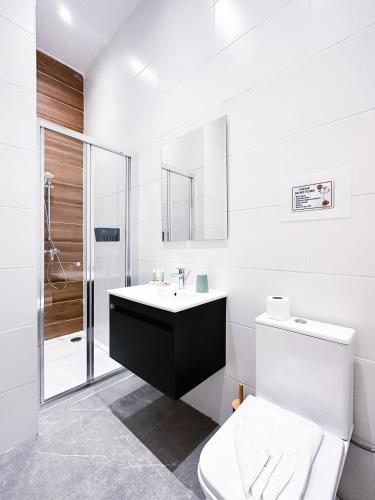 a white bathroom with a sink and a toilet at Valletta Waterfront Backyard Flat by ArcoBnb in Il-Furjana