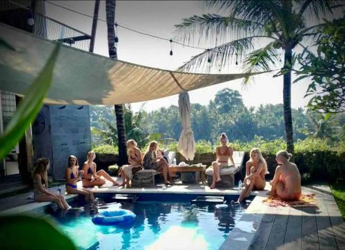 a group of people sitting around a swimming pool at Balitri - hidden gem 9BR service villa hall pool sauna in Sukawati