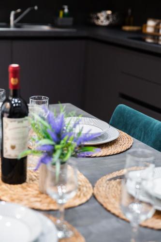 a table with a bottle of wine and flowers on it at Valletta Waterfront Backyard Flat by ArcoBnb in Il-Furjana