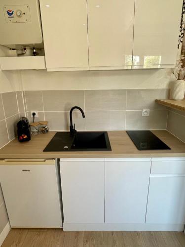 une cuisine avec des armoires blanches et un évier dans l'établissement L’évasion - Studio cosy en centre ville, à Rennes