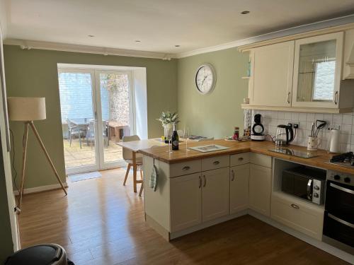 a kitchen with a table and a clock on the wall at Pretty Ground Cottage in Comrie in Comrie