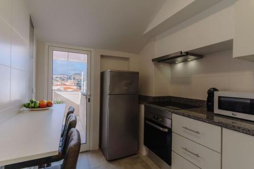a kitchen with a refrigerator and a table with a window at SUPER Oldtown in Funchal