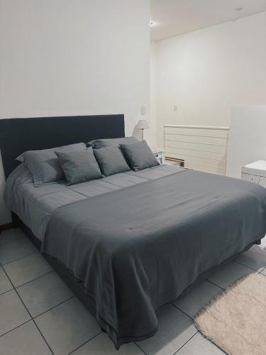 uma cama grande num quarto branco com um cobertor cinzento em El Mensú Loft em Posadas