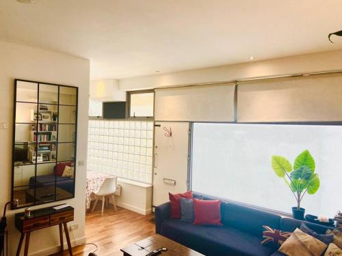 a living room with a blue couch in front of a window at Shoreditch apartment with lovely garden in London