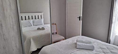 a mirror in a bedroom with a bed and a chair at Grassland 4 (Townhouse) in Bloemfontein