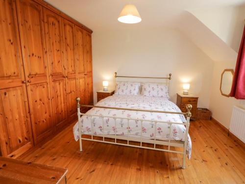 1 dormitorio con 1 cama con paredes de madera y suelo de madera en Craiglea Cottage, en Coleraine