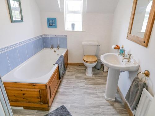 a bathroom with a tub and a toilet and a sink at Craiglea Cottage in Coleraine